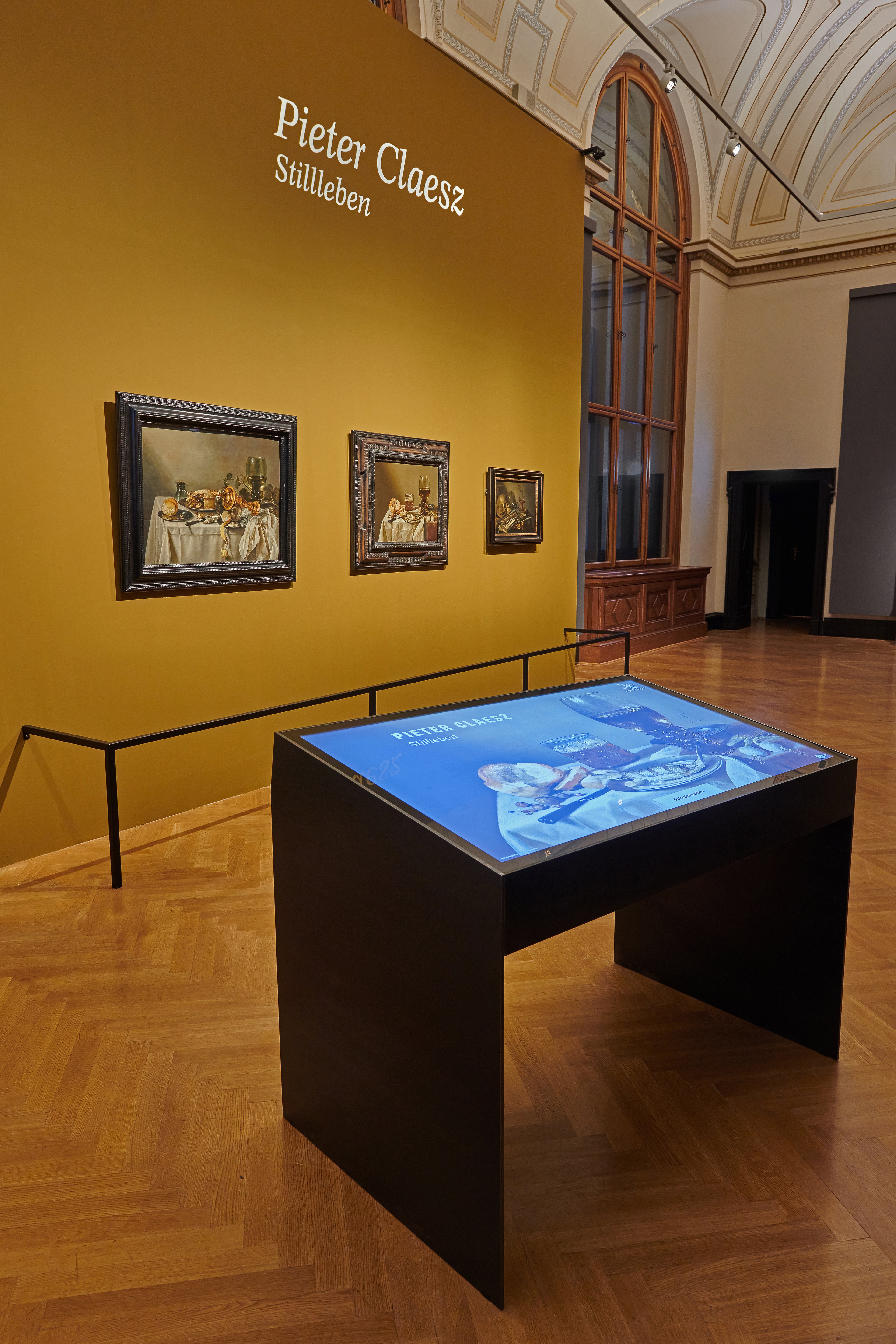 Dieses Foto zeigt den Digitalen Tisch im Kunsthistorischen Museum sowie die drei ausgestellten Stillleben von Pieter Claesz. 
